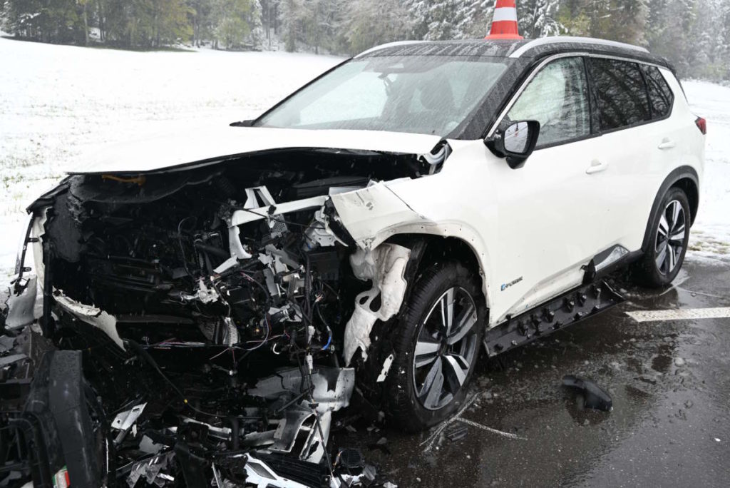 weißes Auto, der Frontbereich stark beschädigt, im Hintergrund Schnee