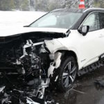 weißes Auto, der Frontbereich stark beschädigt, im Hintergrund Schnee