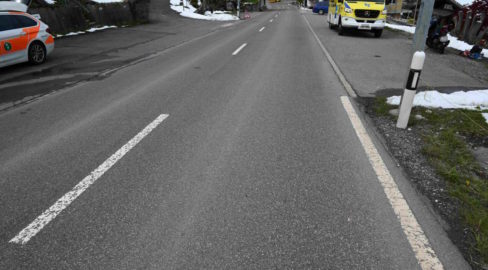 Unfallfoto: Neben einer wieder freien Dorfstrasse steht links ein Polizeiauto und rechts ein Rettungsdienstwagen