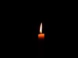 brennende Kerze vor schwarzem Hintergrund